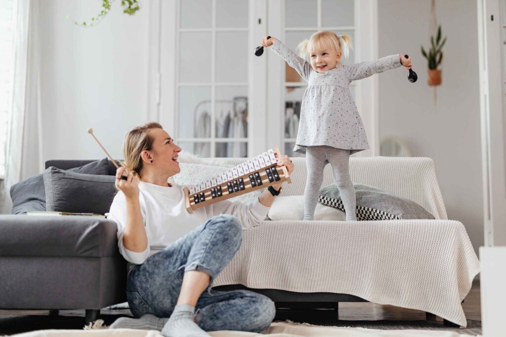 Une maman tenant un xylophone regarde sa fille danser